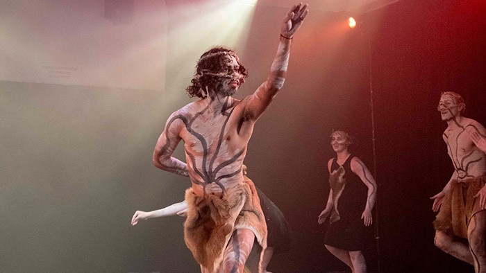A male Aboriginal dancer on stage in a traditional outfit