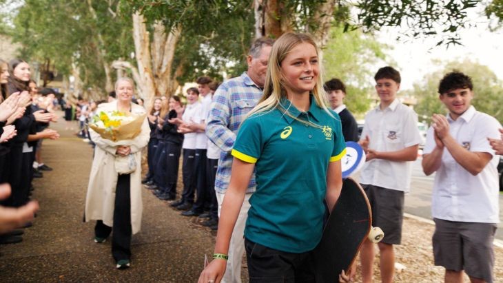 A girl walking down a footpath surrounded on both sides by other students.