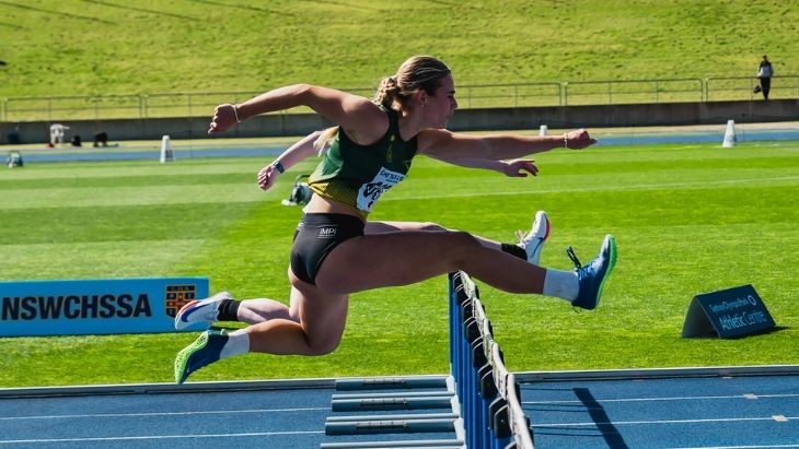 Girls jumping over hurdles.