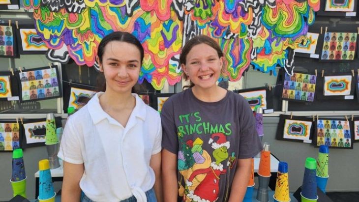 Two students in front of an artwork.