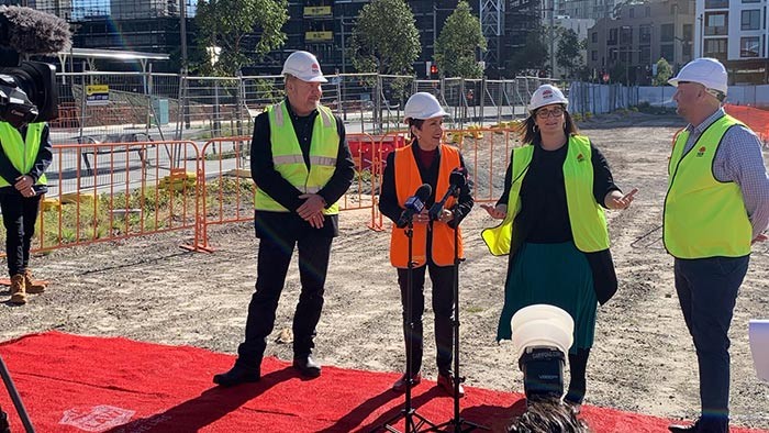 Four adults in hard hats in an open space with red carpet beneath them