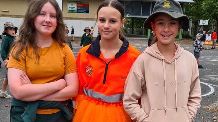 Three girls dressed in orange standing looking at the camera.