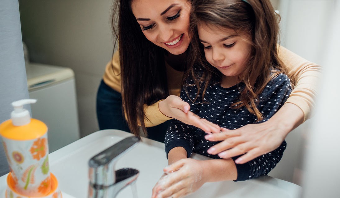 A mother and daughter wash their hands with soap.