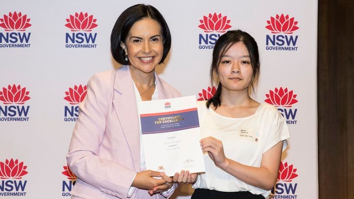 A female student being presented with a certificate by a woman.