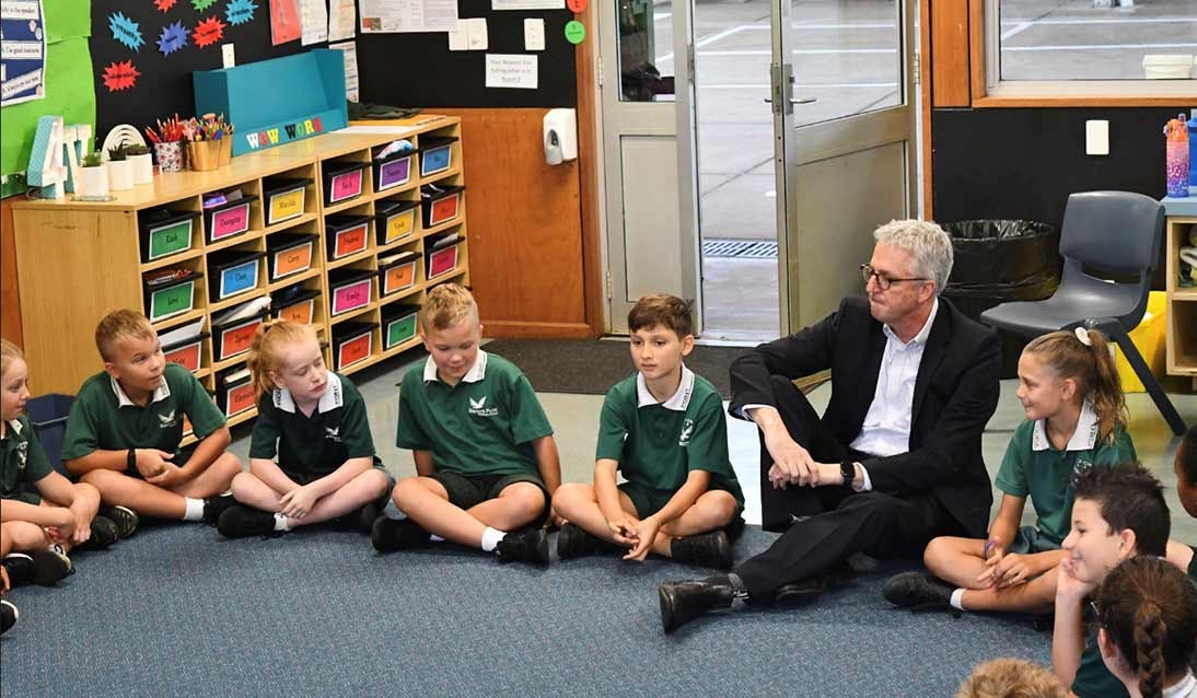 Mark Scott sitting on the floor with students