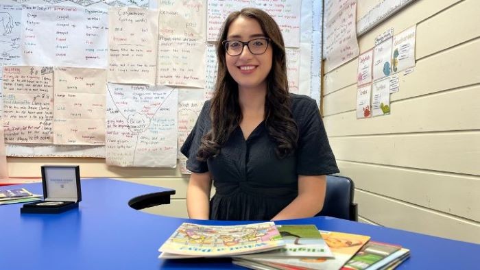 Teacher smiling and sitting behind her desk in the classroom