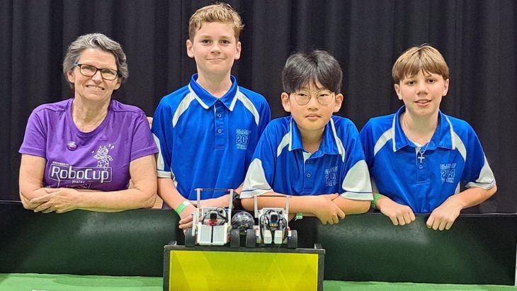 A teacher with students and two Lego robots.