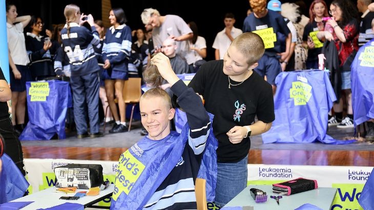 A student has their head shaved.