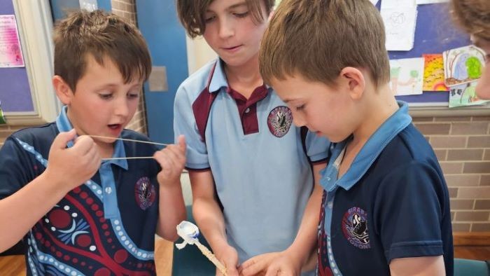 Three students making a toy catapault