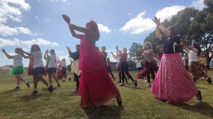 A group of girls in a field dancing in Bollywood style