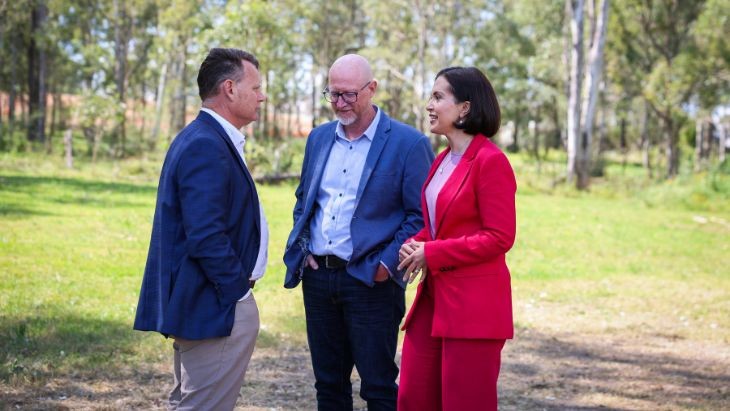 Two men and a woman speaking in a paddock.