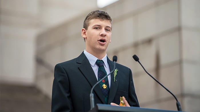 Student in uniform standing in front of a microphone speaking