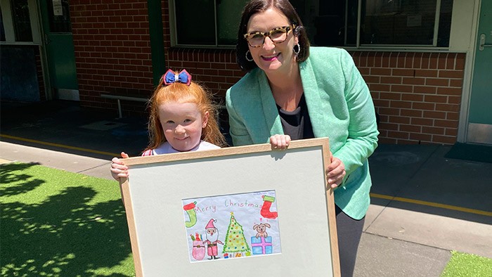 Young school student holding a framed picture next to Minister for Education 