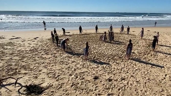 Students perform a traditional dance on the beach