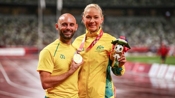 A man holding a medal with a woman holding a soft toy.