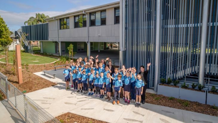 Students and teachers waving out the front of a school building.