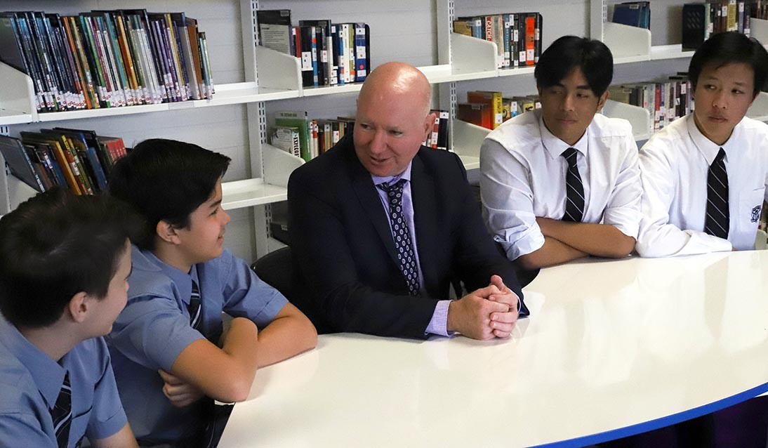 Principal and four students sitting at a table talking.