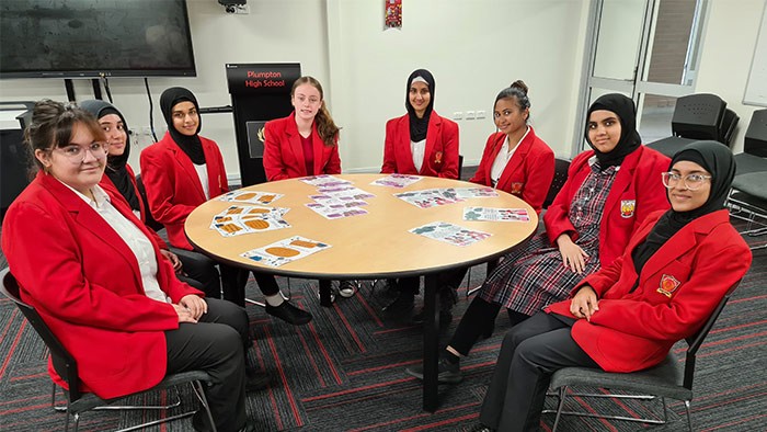 A group of young women in school uniform sit around a table