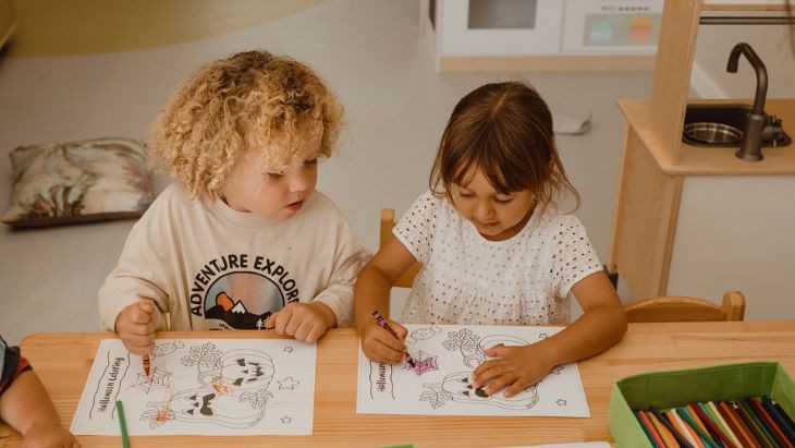 Two students colouring in at a desk.