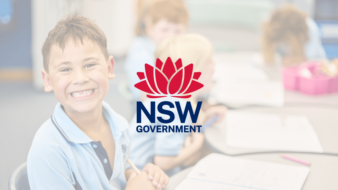 A smiling student sitting at a desk.