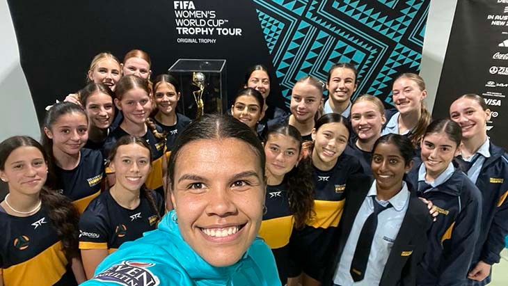 A young female soccer player takes a selfie with female students.
