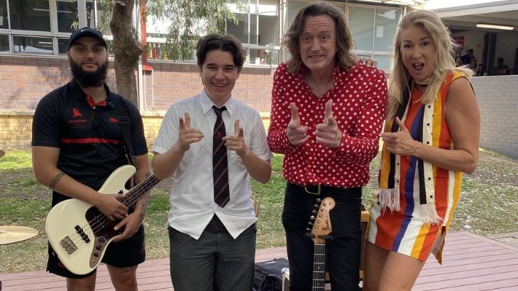 A student and adults holding instruments and pointing their fingers.