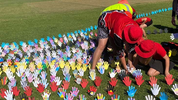 Students planting coloured hands in the ground.