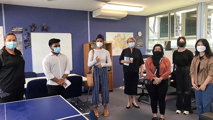 A group of people wearing masks standing in a classroom