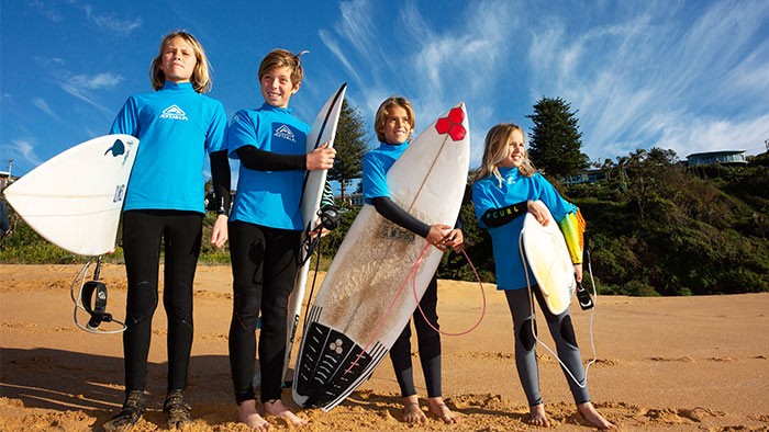 Four kids on a beach with surfboards