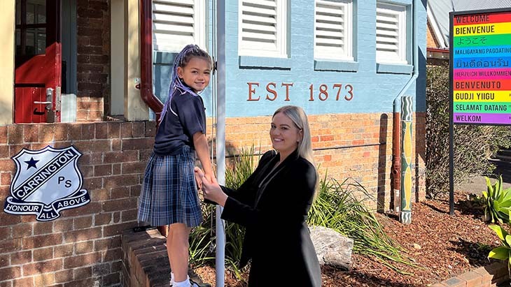 A student standing on a wall while her mum holds her hands.
