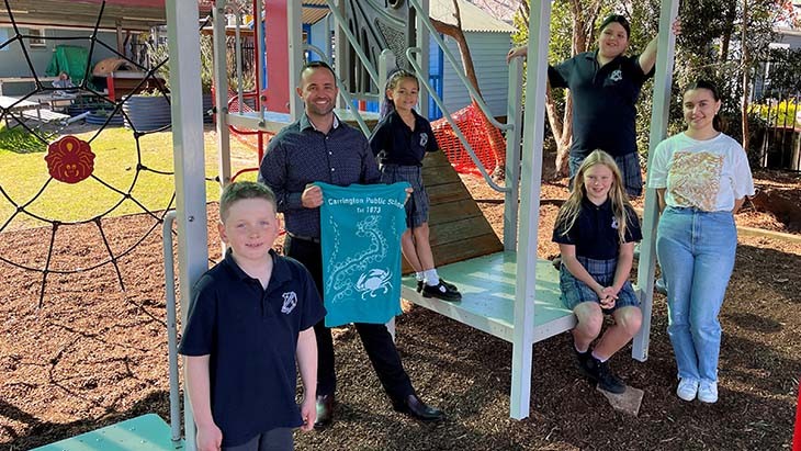 Staff and students standing on and in front of play equipment.