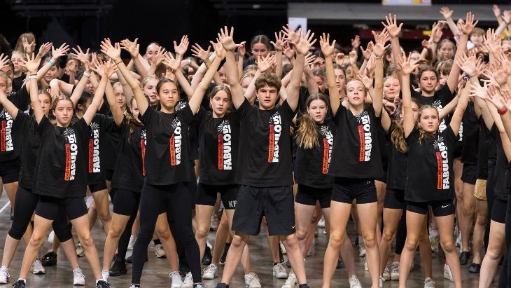 Students in matching black shirts with their hands in the air.