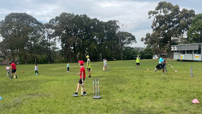 A group of children playing cricket on a school oval