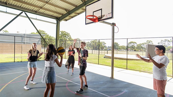 A group of students playing basketball at a school court