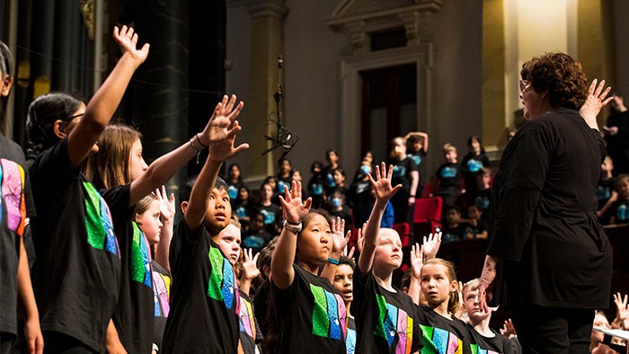 A group of students in a choir with the conductor using sign language in their performance