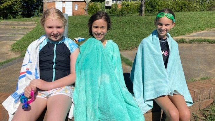 Three young girls sitting looking at the camera wrapped in towels