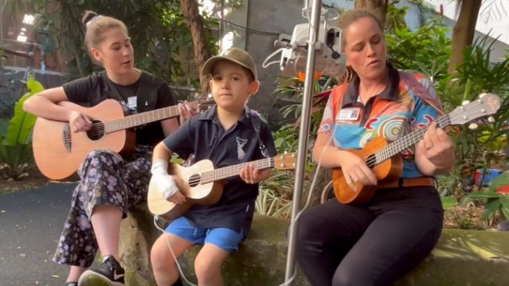 Two adults and a student playing guitars.