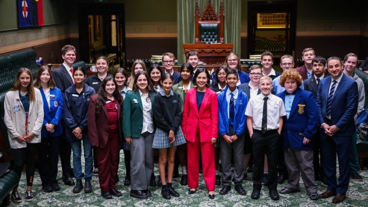 A group of people standing in the chamber of the NSW Parliament.