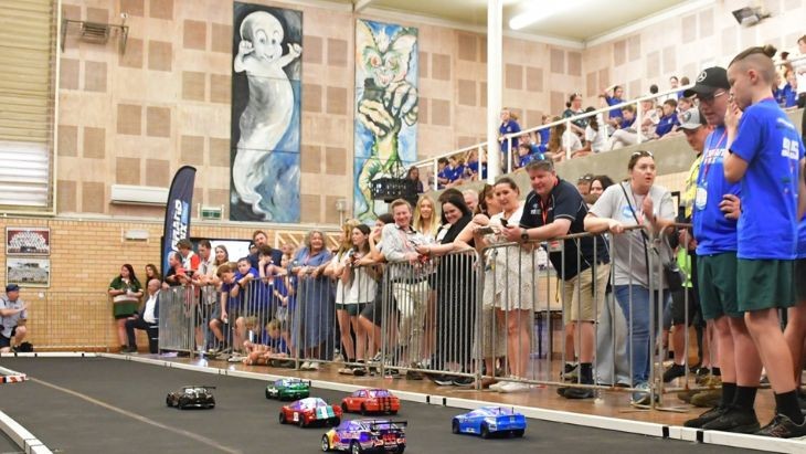 Students watching cars race on a track.