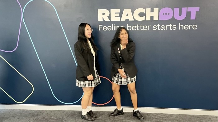 two girls laughing in front of a sign