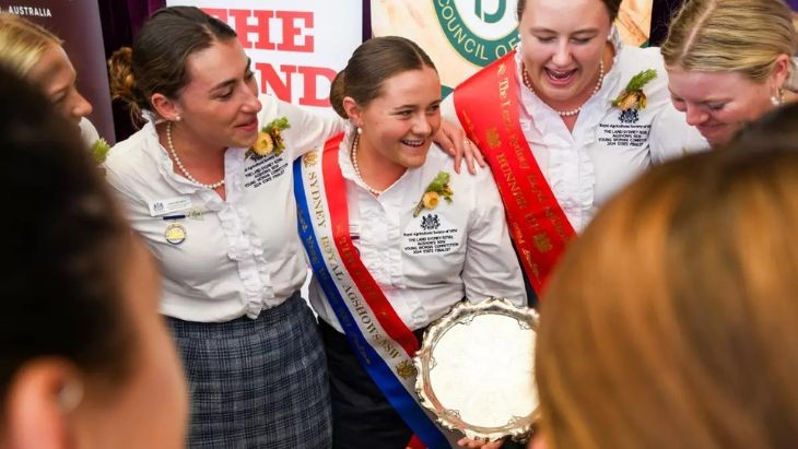 A woman holding a trophy standing next to two other women.