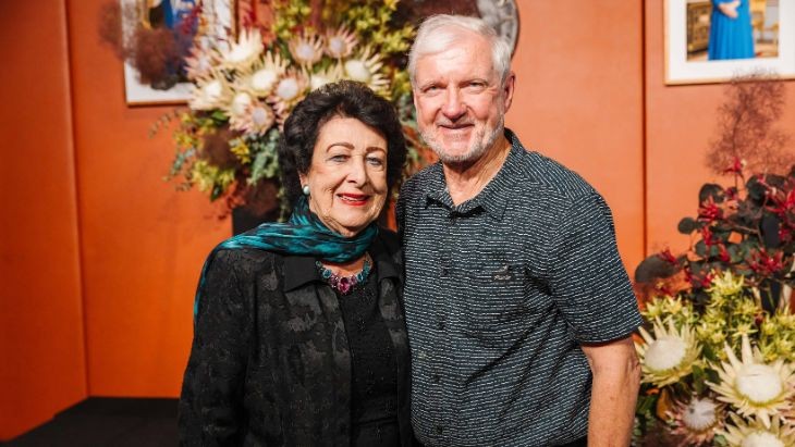 A man and woman in front of a bunch of flowers.