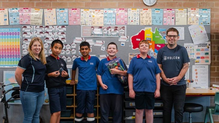 Teachers and students standing in front of a wall of maps.