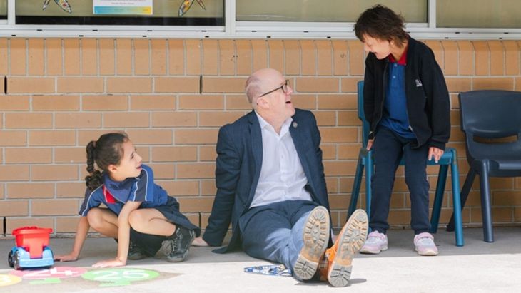 A teacher with two students, one sitting and one standing.