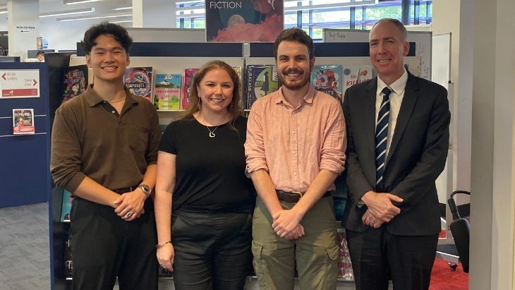 Four people standing in a library.