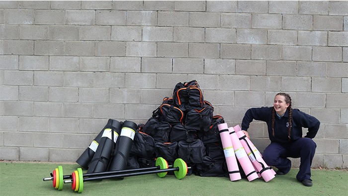 A young woman crouches beside a pile of exercise equipment