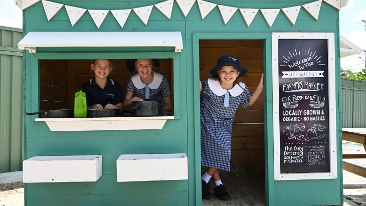 Students standing inside a cubby house.
