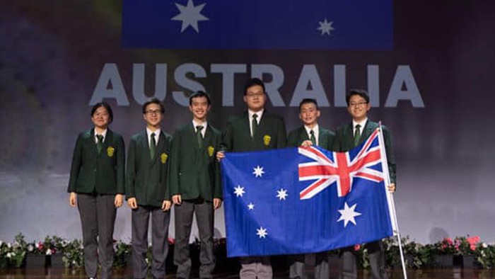 A group of six students with one female on the far left standing with an Australian flag