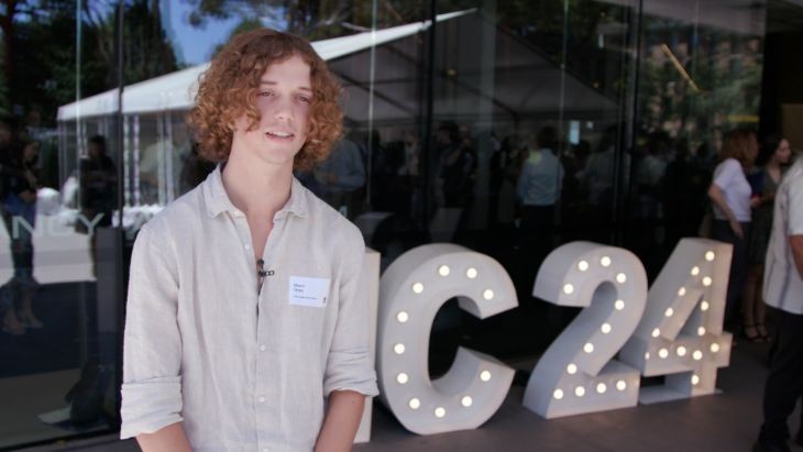 A student standing in front of a sign.