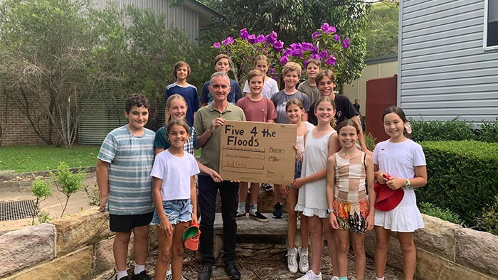 A group of primary students with their principal holding a home-made cheque.